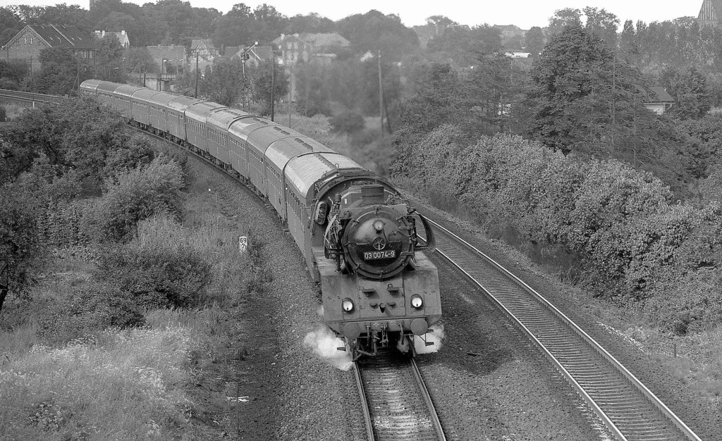 (c) Hans van Poll - 03 0074 (03 1074, Krauss-Maffei 15724/1940/1959/1965, Bw Stralsund), neben der 03 0010 die andere 03.0 mit Röhrenvorwärmer, am 2.8.1977 vor D 715 (Putbus - Leipzig) kurz nach der Abfahrt aus Angermünde. Dieser Zug benutzte nicht die Verbindungskurve bei Stralsund Rügendamm von Rügen direkt auf die KBS 920 (Berlin-Lichtenberg - Angermünde - Pasewalk - Stralsund, ab 1992 290/190) sondern machte Kopf in Stralsund.